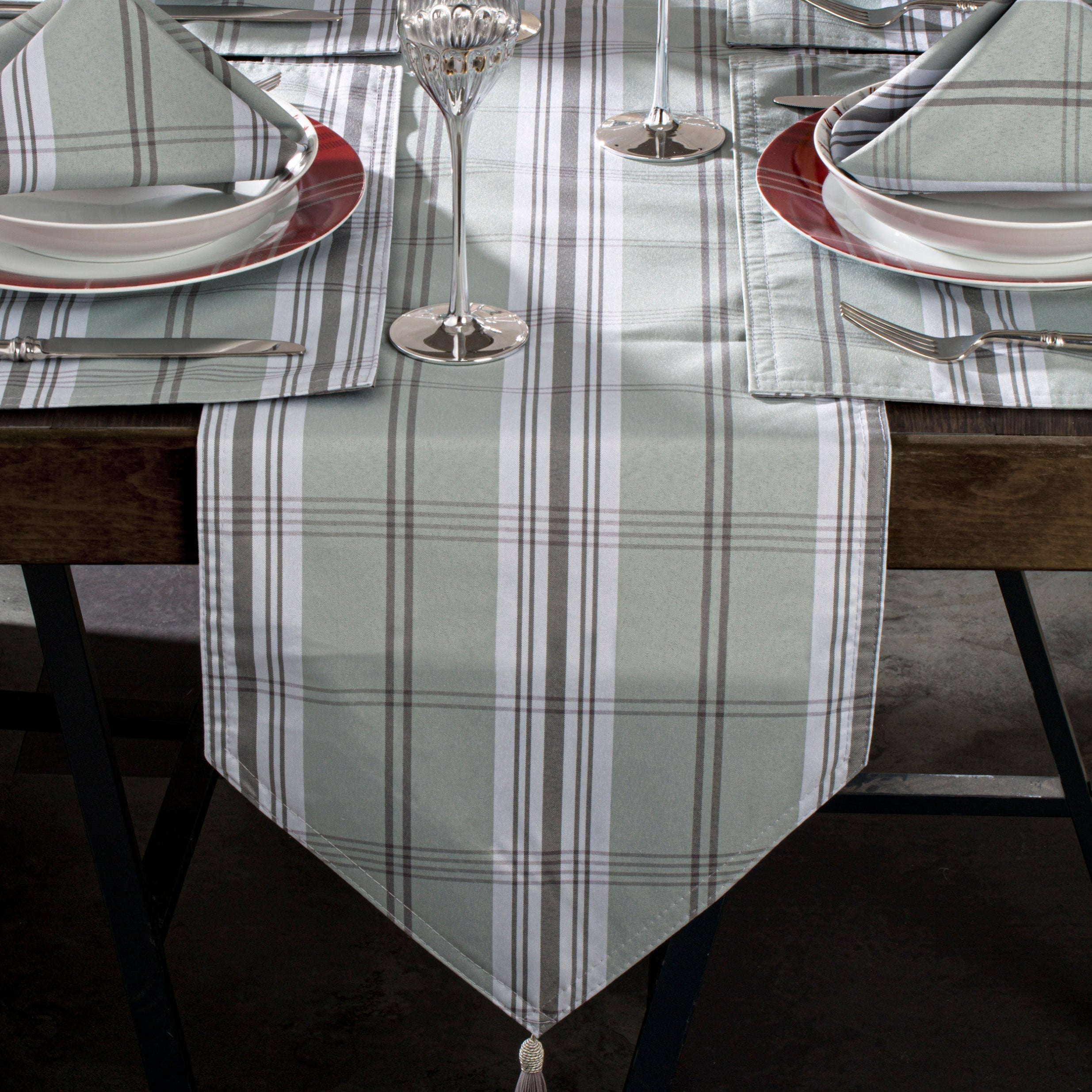 A table setting with a grey tartan table runner, six placemats, and square napkins.