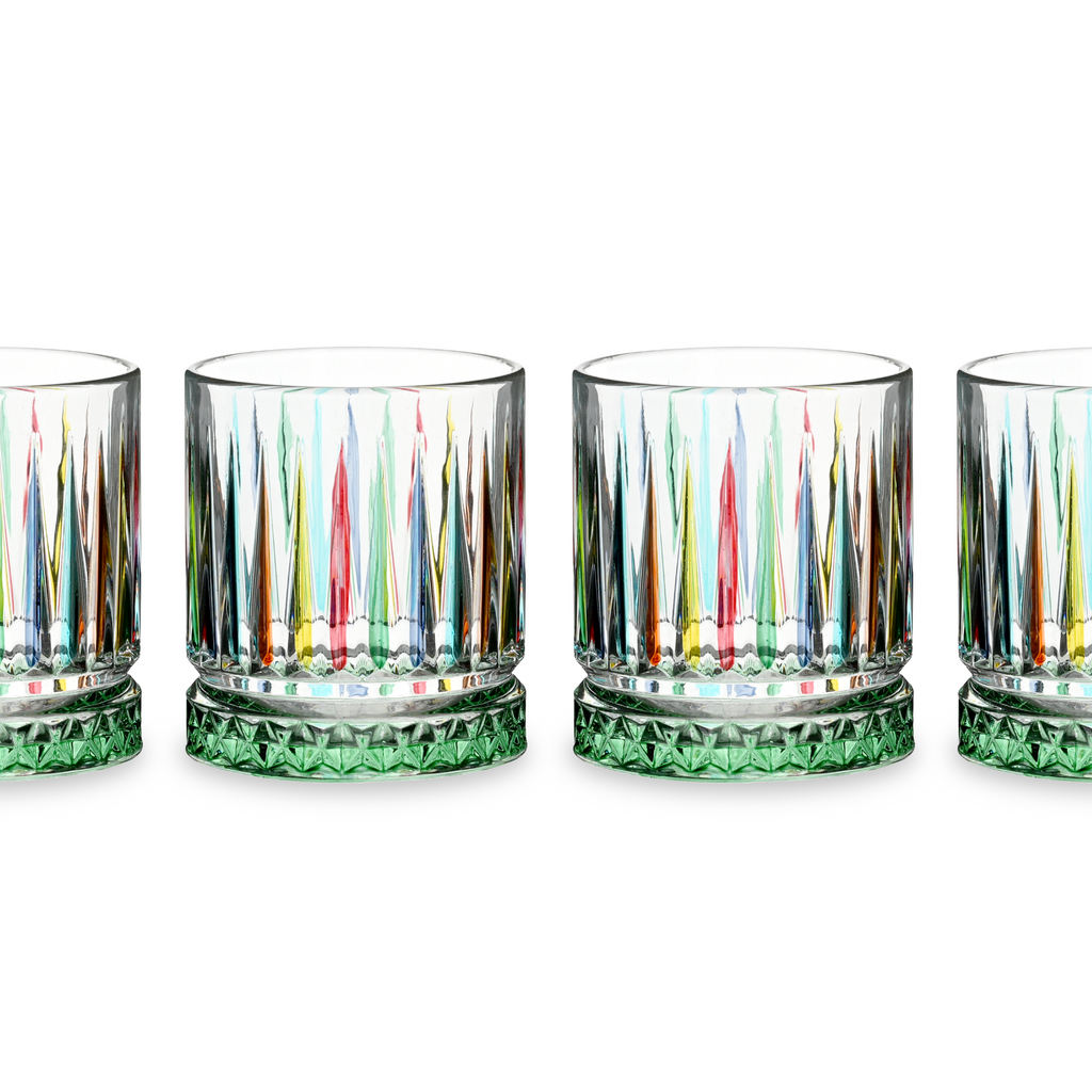Set of four colorful glass tumblers with green bases on a white background